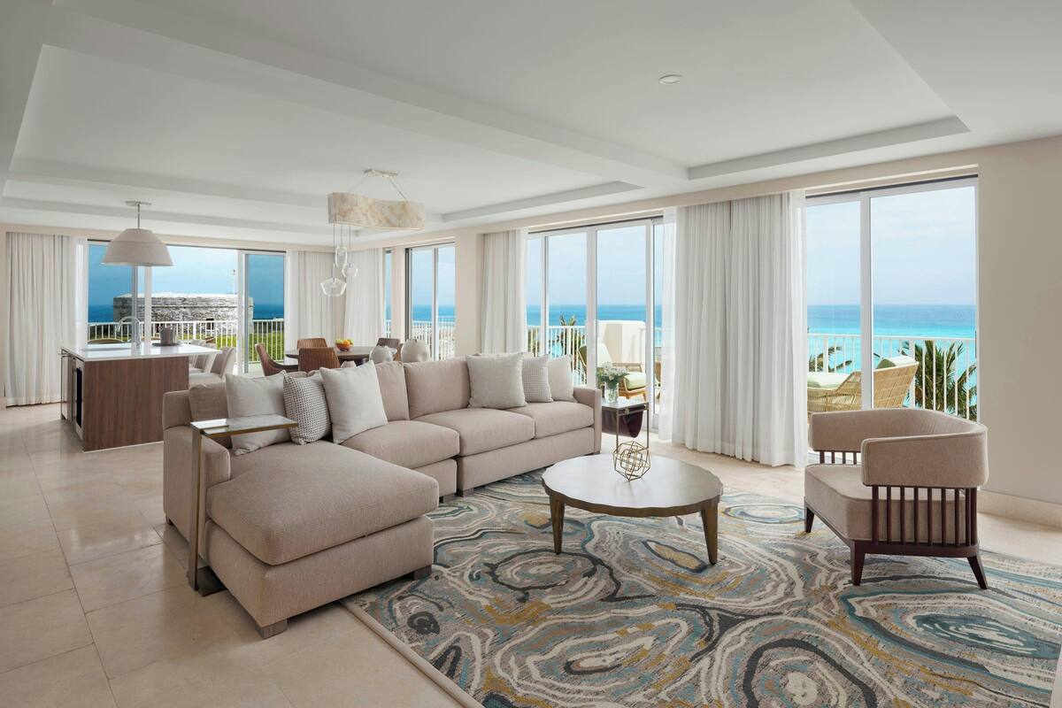 A spacious living room with a large sofa, a round coffee table, and a view of the ocean.