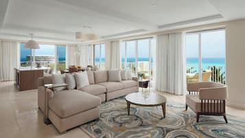 A spacious living room with a large sofa, a round coffee table, and a view of the ocean.