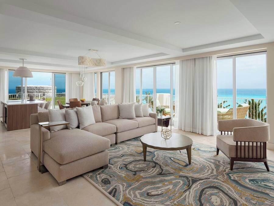 A spacious living room with a large sofa, a round coffee table, and a view of the ocean.