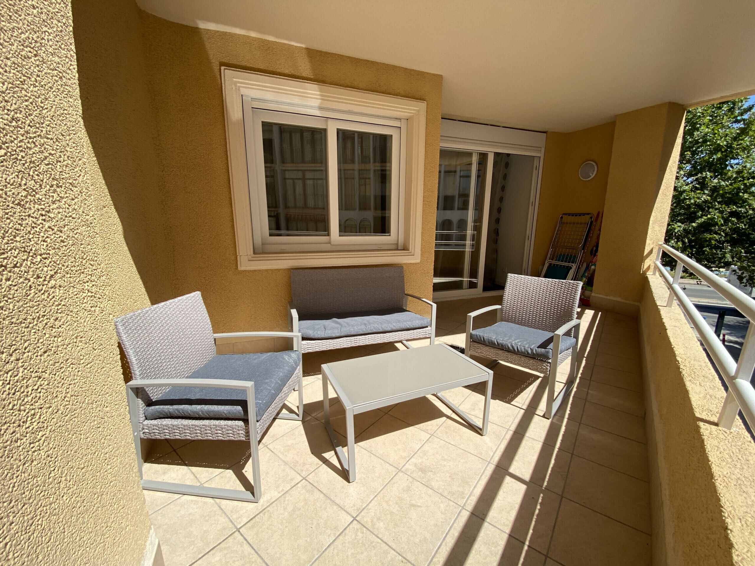 A balcony with two sofas, a small table, and a chair.