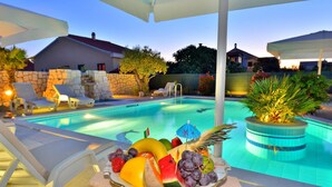 Zona de piscina con sillones de descanso, un frutero y una pared de piedra.