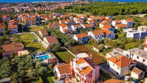 Un barrio residencial con casas, una piscina y vista al mar.