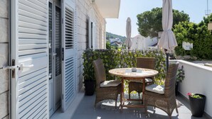 A balcony with a round table, wicker chairs, and a large umbrella. - Apartments K & N (Blato)