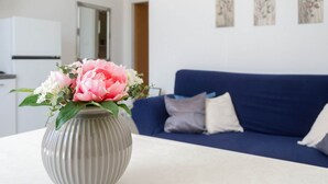 A living room with a grey vase on a white table, a blue sofa with cushions, and a white cabinet. - Apartments K & N (Blato)