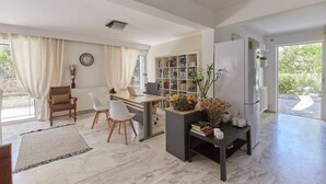 A modern kitchen with a dining area, a bookshelf, and a refrigerator. - Harmony Vale- Anavissos (Saronikos)