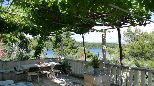 A terrace with a pergola, outdoor seating, and a view of the sea. - Apartment Kim (Lumbarda)
