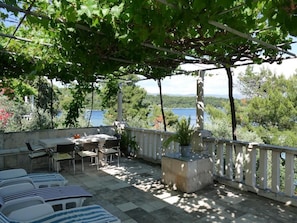 A terrace with a pergola, outdoor seating, and a view of the sea.