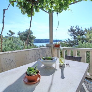 A balcony with a table, potted plants, a teapot, and a bottle.