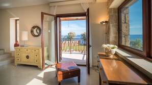 Una habitación con un banco de madera, un aparador amarillo y vista al mar a través de un ventanal.