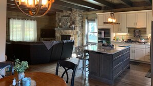 A spacious kitchen with a large island, stone accents, and modern appliances. - Sweets River Nest-riverfront/tube/hot tub/log cabin-fishing- Valle Crucis/App ST (Banner Elk)