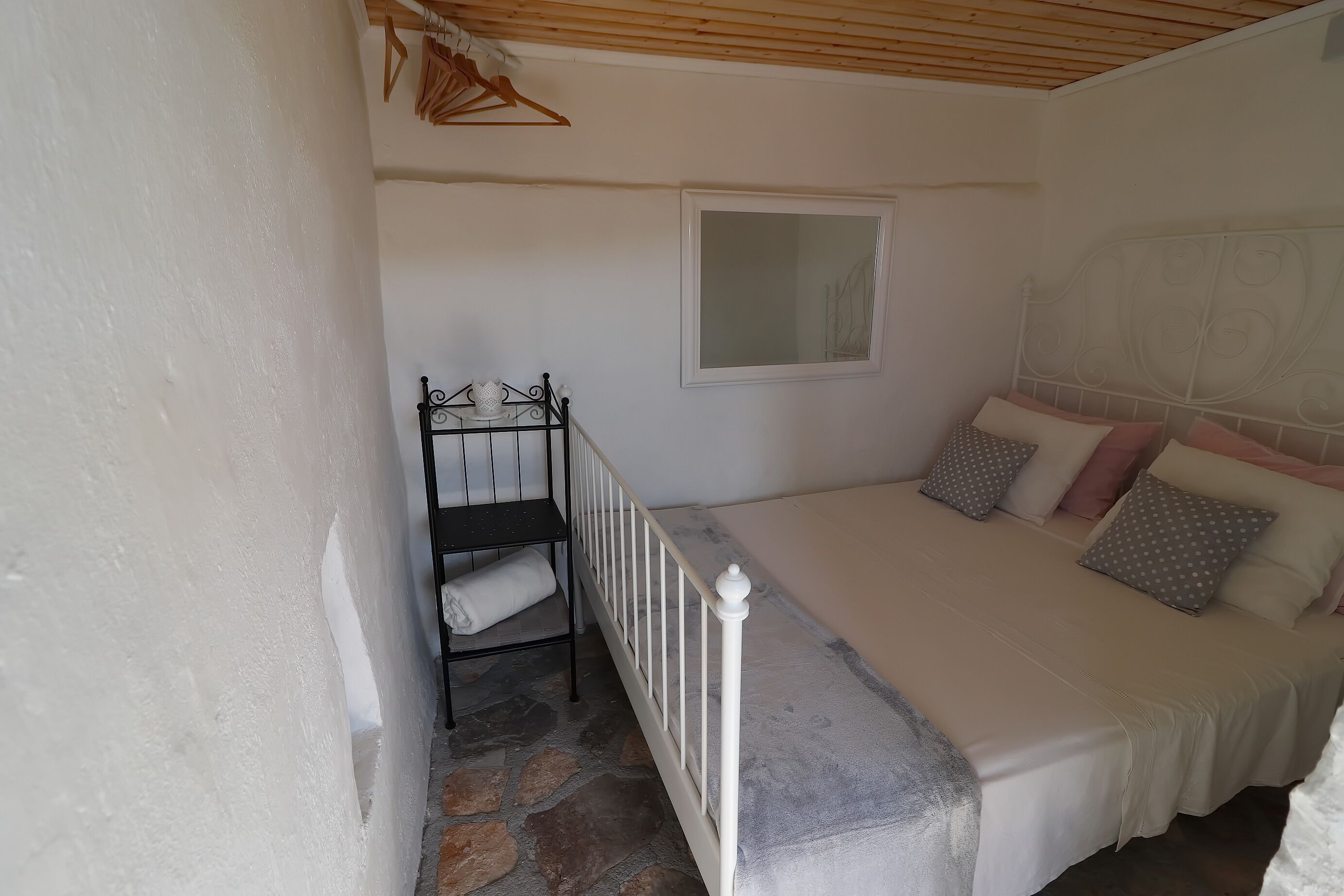 Une chambre à coucher avec un lit, une fenêtre et une étagère en métal sur laquelle est posée une serviette.