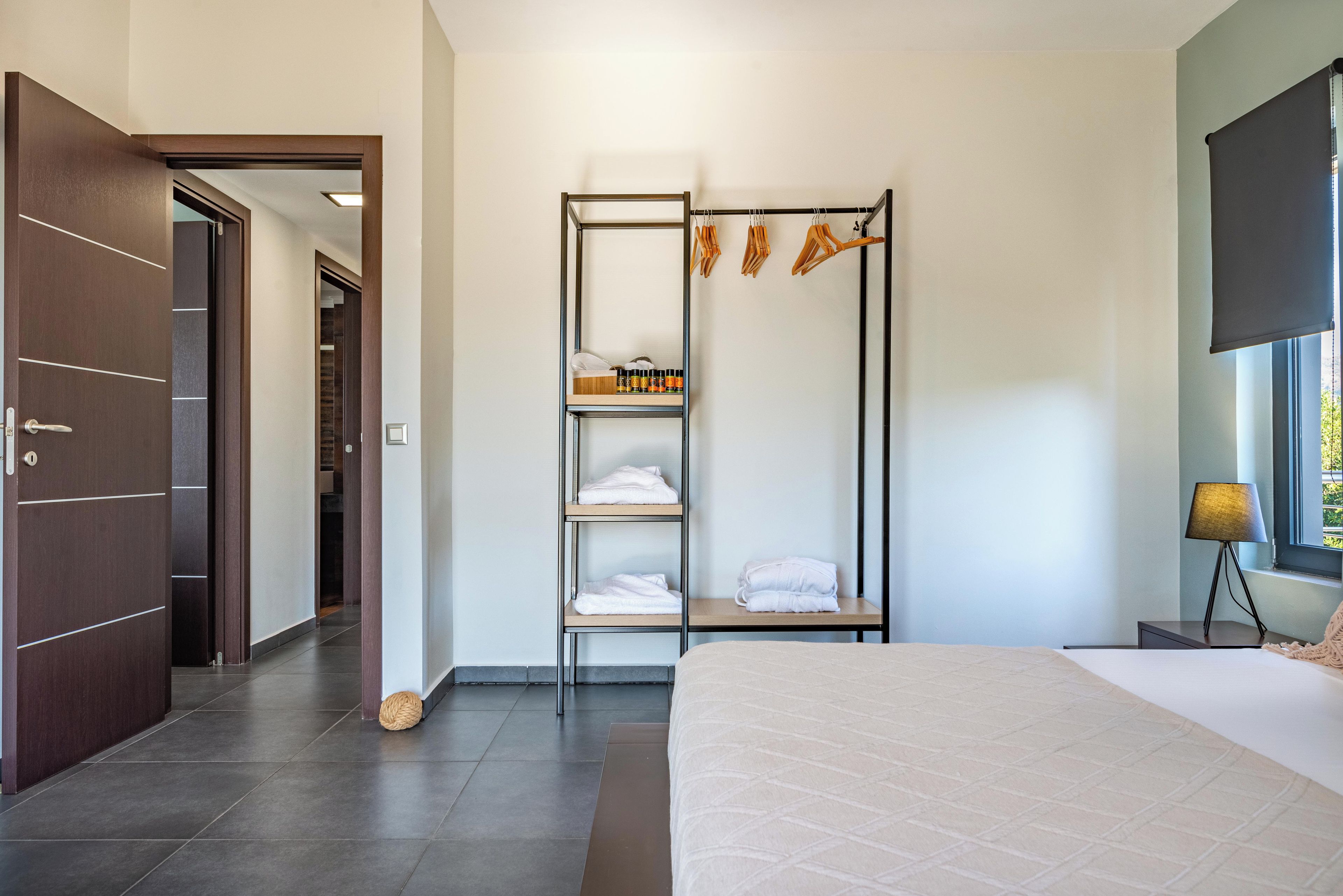 Ein modernes Schlafzimmer mit einem Bett, einem Kleiderschrank, einer Ablage mit Handtüchern und einem Fenster mit Aussicht.