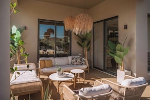 An outdoor patio area with wicker furniture, a sofa, and a hanging light fixture. - Villa Vega - Holiways Collection (Platanias)