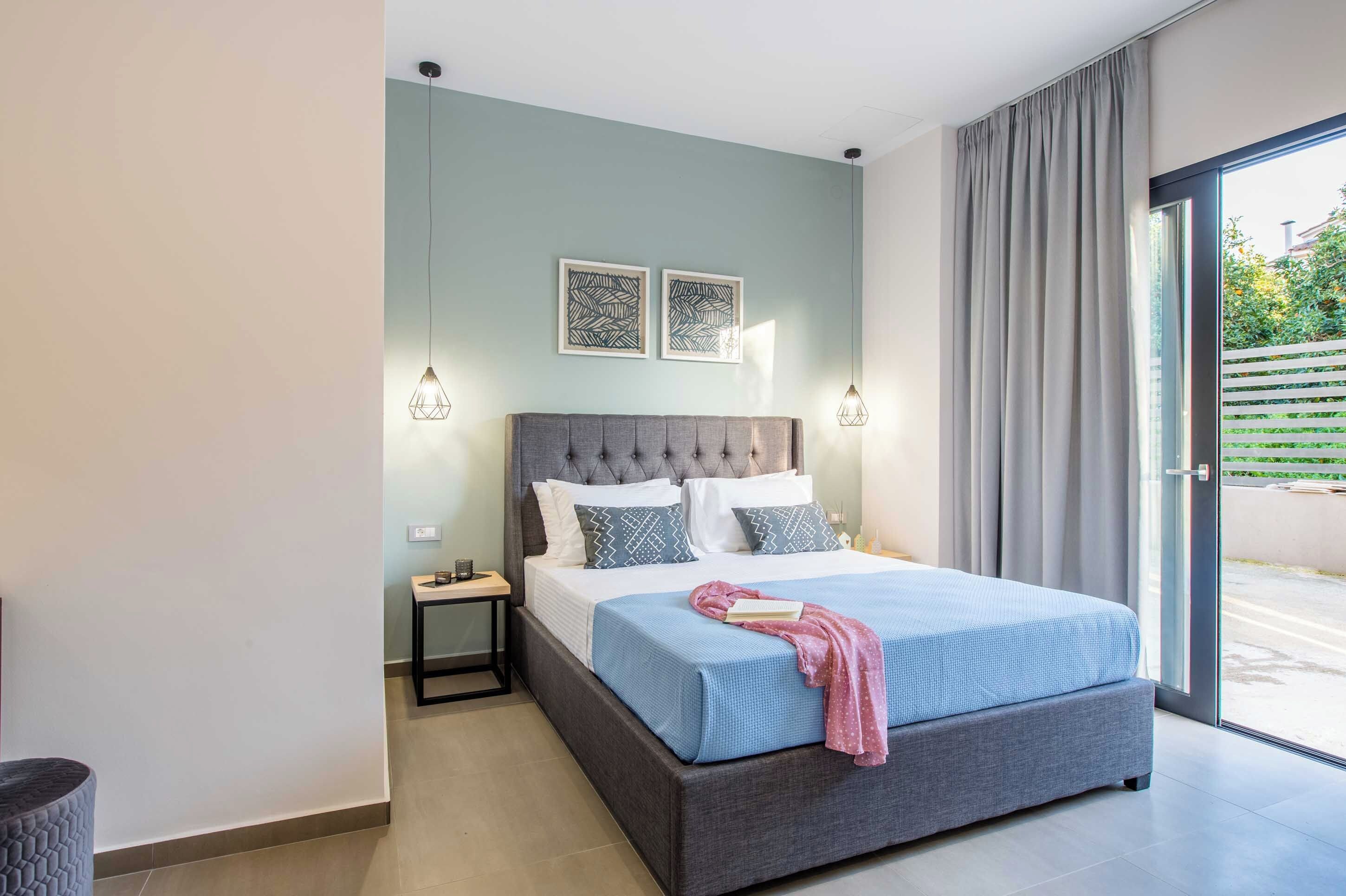 Quarto moderno com uma cama grande, duas luzes fixadas na parede e duas obras de arte emolduradas.