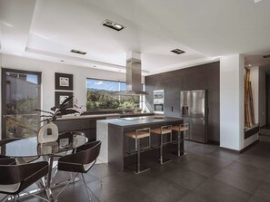 A modern kitchen with a large island, stainless steel appliances, and a view of the outdoors.