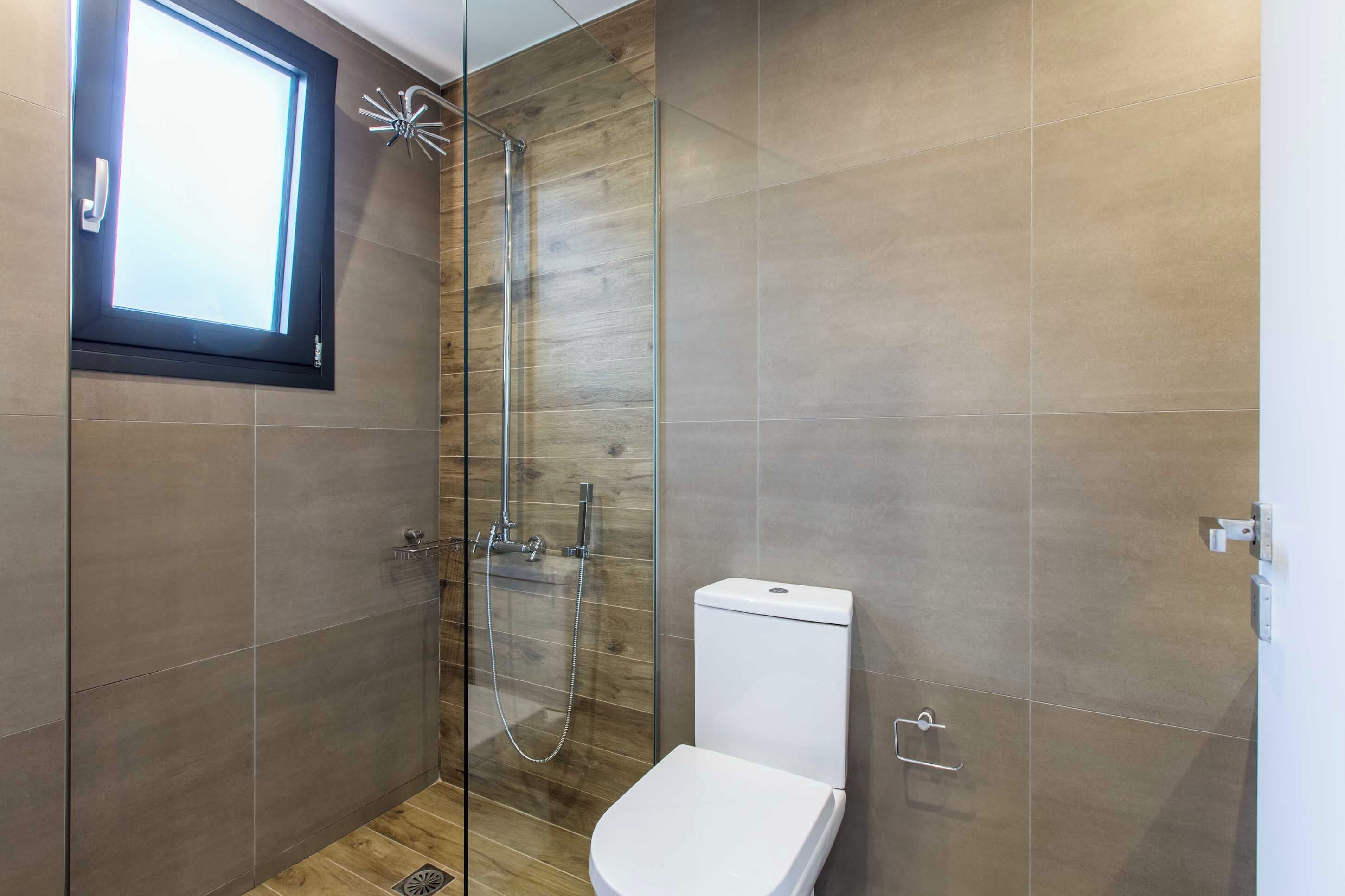 Un baño moderno con ducha de vidrio, inodoro y ventana.