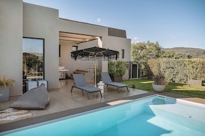 A modern outdoor pool area with two lounge chairs and a covered seating area. - Villa Vega (Platanias)