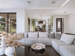 A modern living room with a sectional sofa, a coffee table, and a dining area with a chair and table.