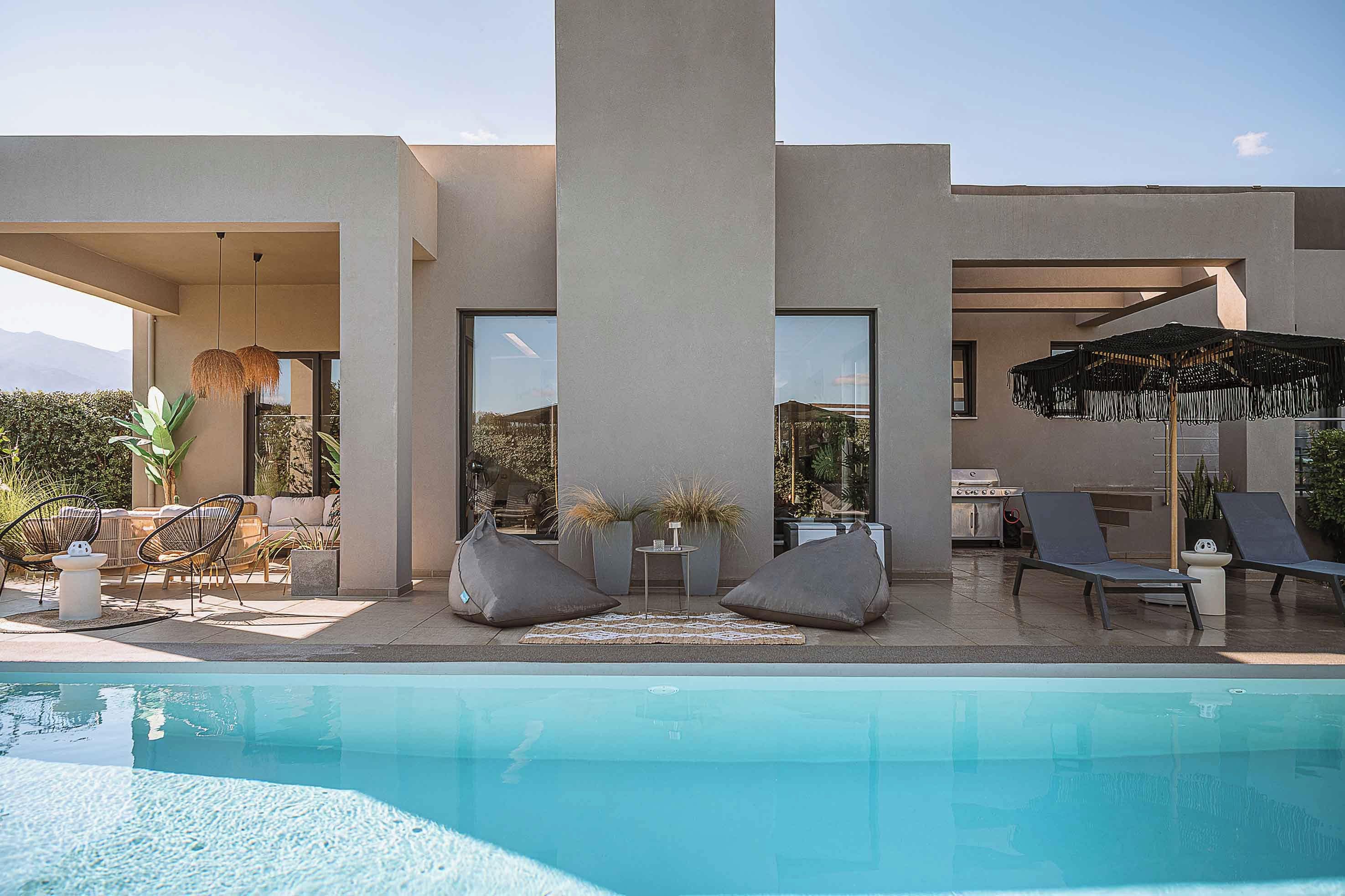 Un área moderna junto a la piscina, con piscina, sillas de descanso y una parrilla.
