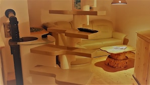 A room with a wooden coffee table, a sofa, and a small table with a remote control.