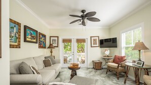 A living room with a sofa, armchairs, a coffee table, a TV, and artwork on the walls.