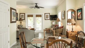 A dining area with a round glass table, wooden chairs, and striped placemats.