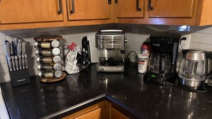 Una cocina con armarios de madera, cafetera, hervidor y varios utensilios de cocina.
