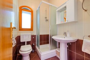 A bathroom with a toilet, shower, sink, and a mirror. - Seafront Holiday Home Marija (Blato)