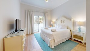 A hotel room with a bed, a TV, a desk, and a window with curtains.