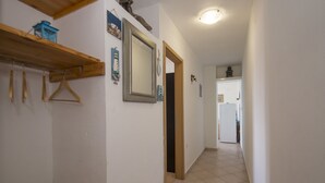 A narrow hallway with a wooden beam and a coat rack on the left. A mirror and a door are visible on the right. - Apartment Slatina (Vela Luka)