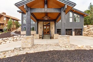 A modern house with a stone facade, large windows, and a covered entrance.