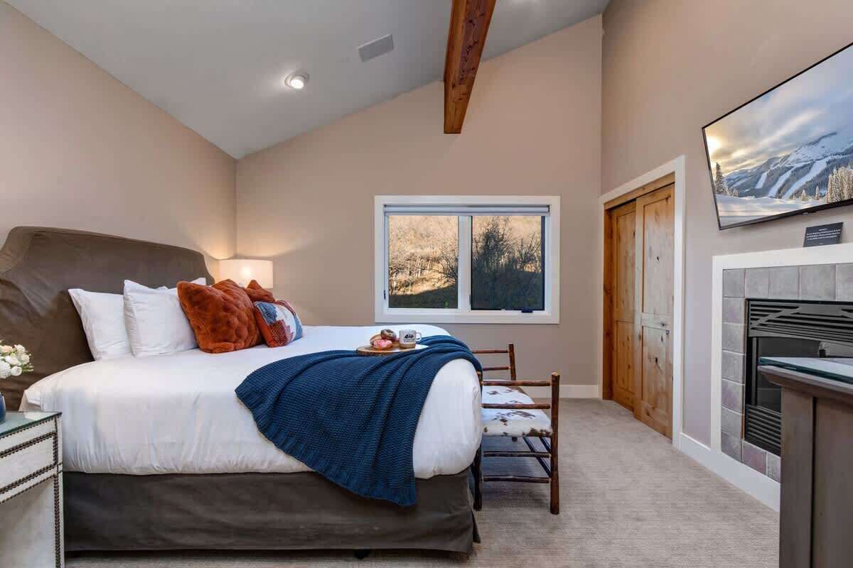 A bedroom with a bed, a window, a television, and a fireplace.
