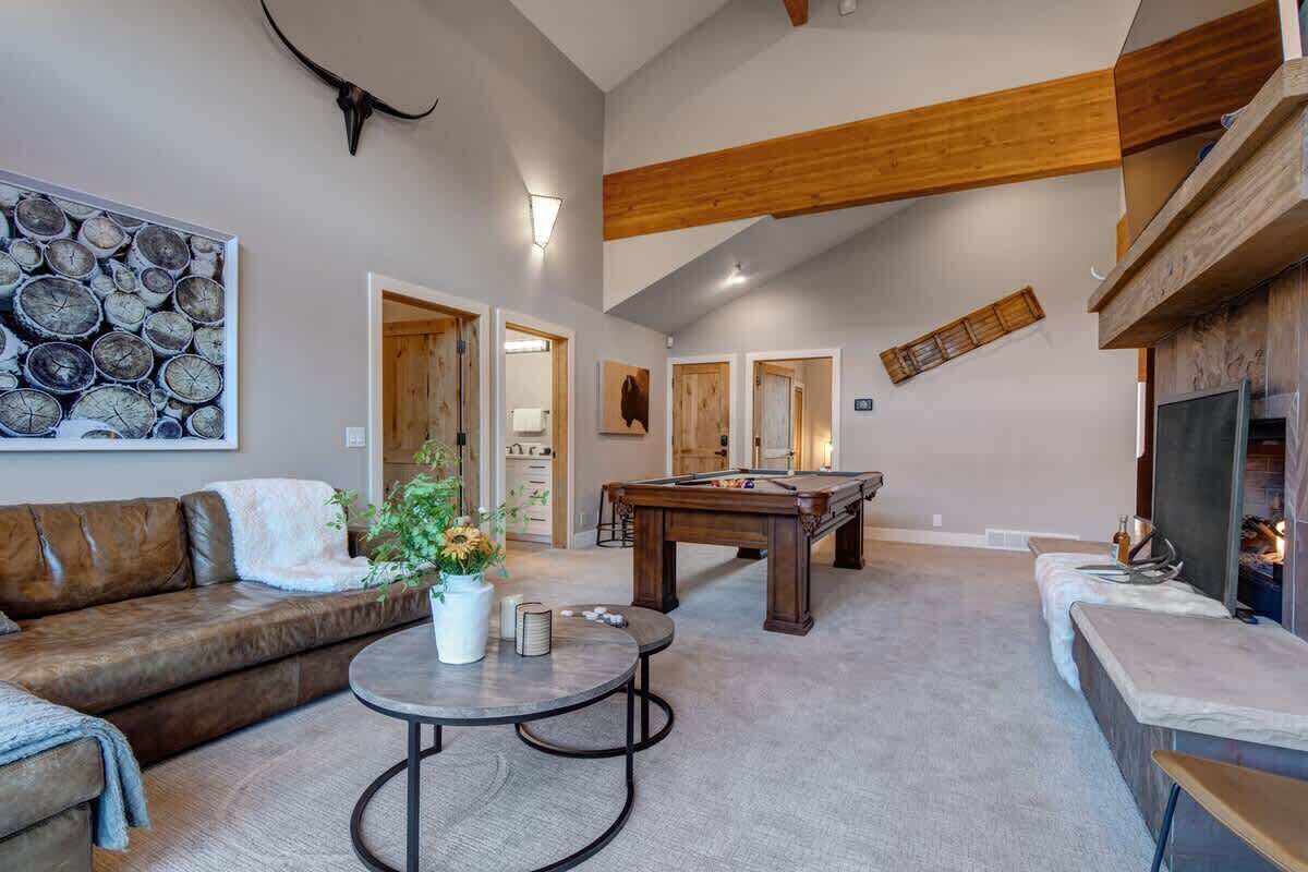 Amplia sala de estar con mesa de billar, sofá, mesa de centro y chimenea.