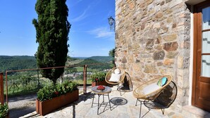 A stone building with a balcony, wicker chairs, a table, and a potted plant. - Gittori, Gaiole in Chianti, Siena and Chianti (Gaiole in Chianti)