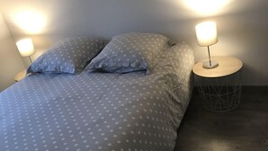 A bedroom with a bed, two bedside lamps, and a round nightstand.
