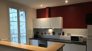A modern kitchen with white cabinets, a black countertop, and a red accent wall.