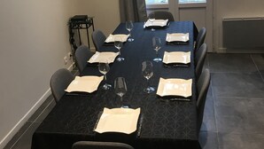 A dining area with a table set for six, chairs, a window with curtains, and a view of the outside.