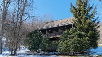 A building with a covered deck, surrounded by snow-covered ground and trees.