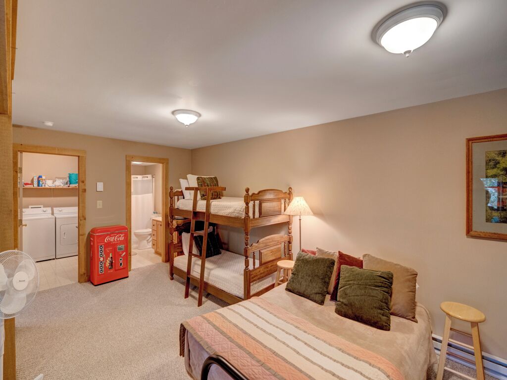 A room with bunk beds, a fan, a Coca-Cola vending machine, and a small stool.