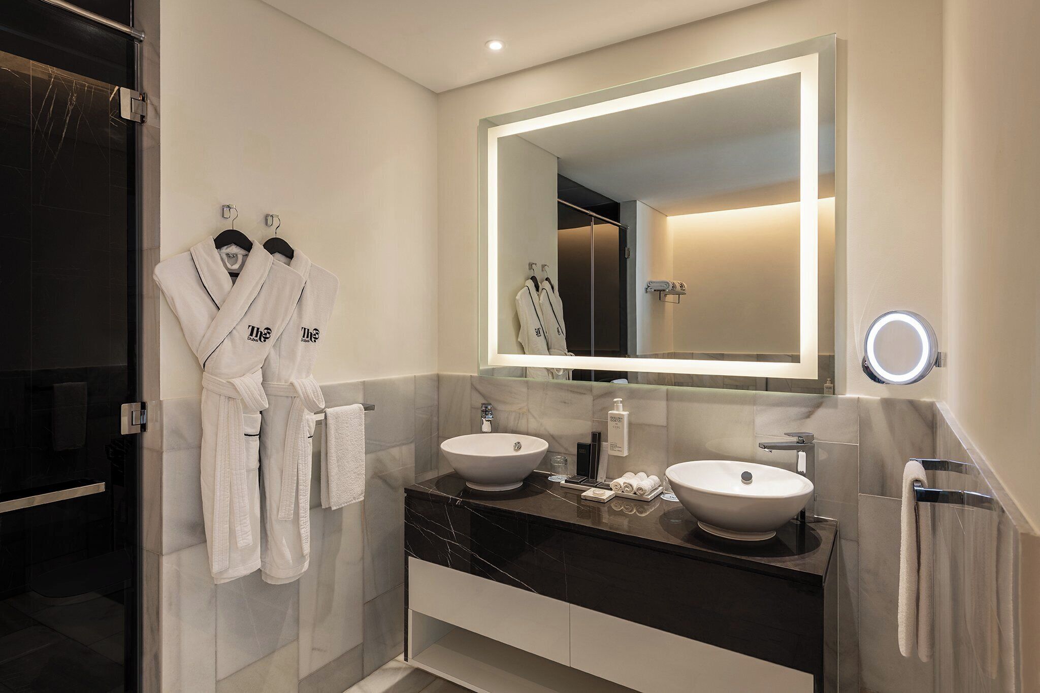 Un bagno moderno con due lavabi, uno specchio grande e un box doccia in vetro.