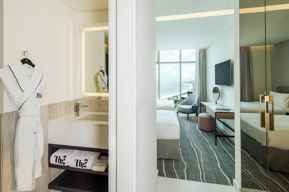Une chambre d’hôtel avec salle de bain, un lit, un bureau et vue sur l’océan.