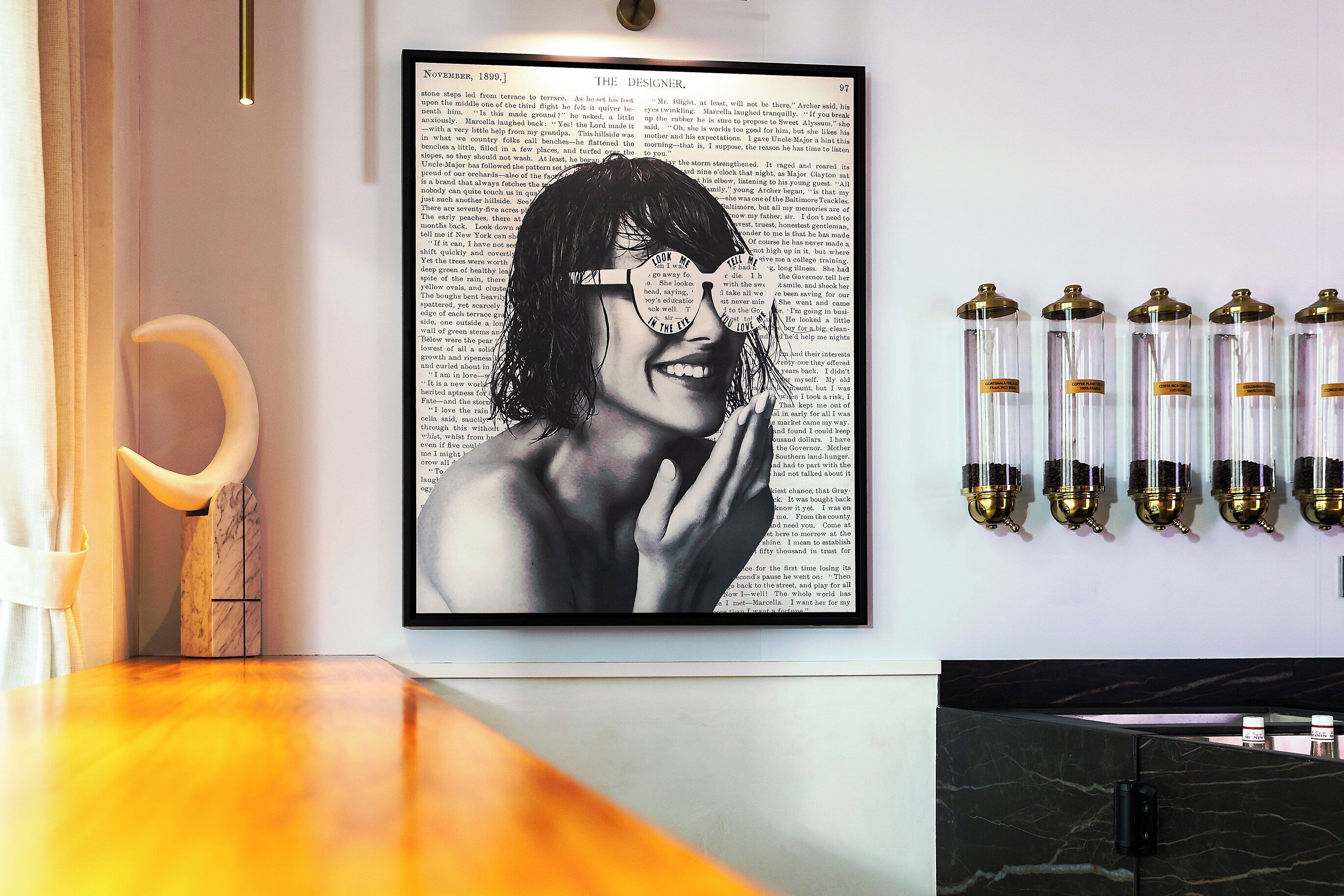 A framed black and white photograph of a person with glasses, a marble sculpture, and a row of cylindrical containers on a wall.