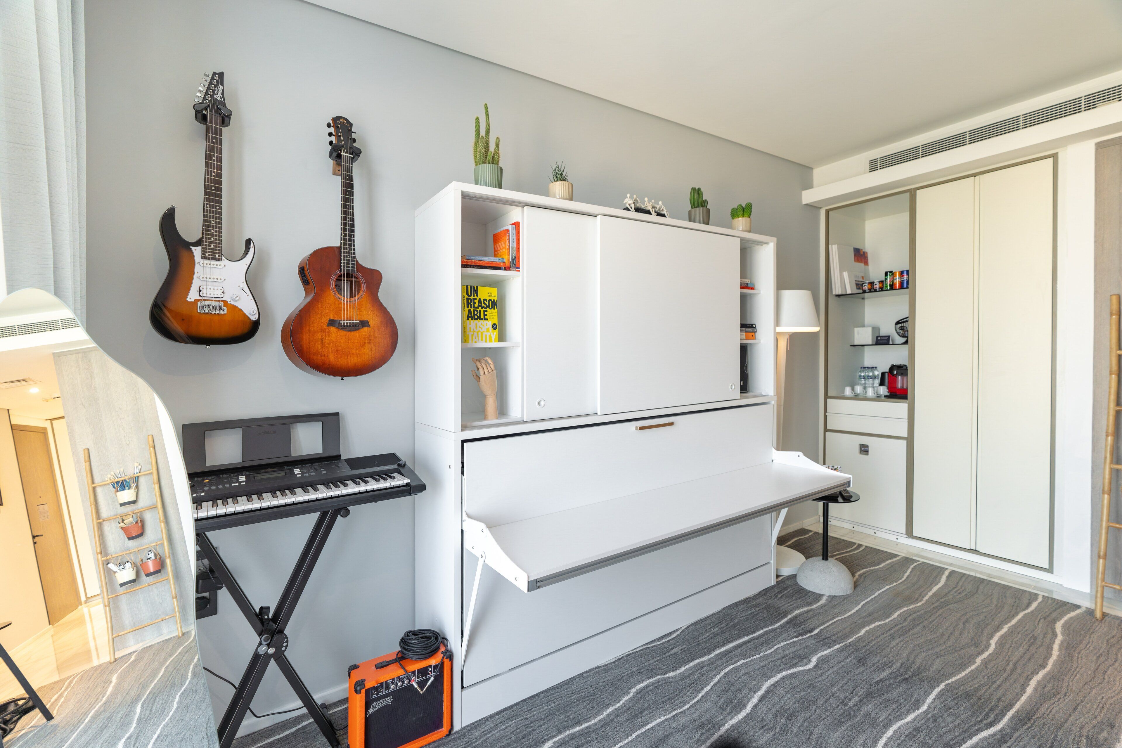 A room with a piano, two guitars, a keyboard, and a small amplifier.