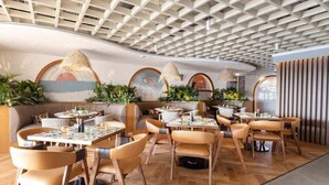 A modern restaurant interior with wooden flooring, leather seating, and a ceiling with a geometric pattern. - Th8 Palm Dubai Beach Resort, Vignette Collection by IHG (Dubai)