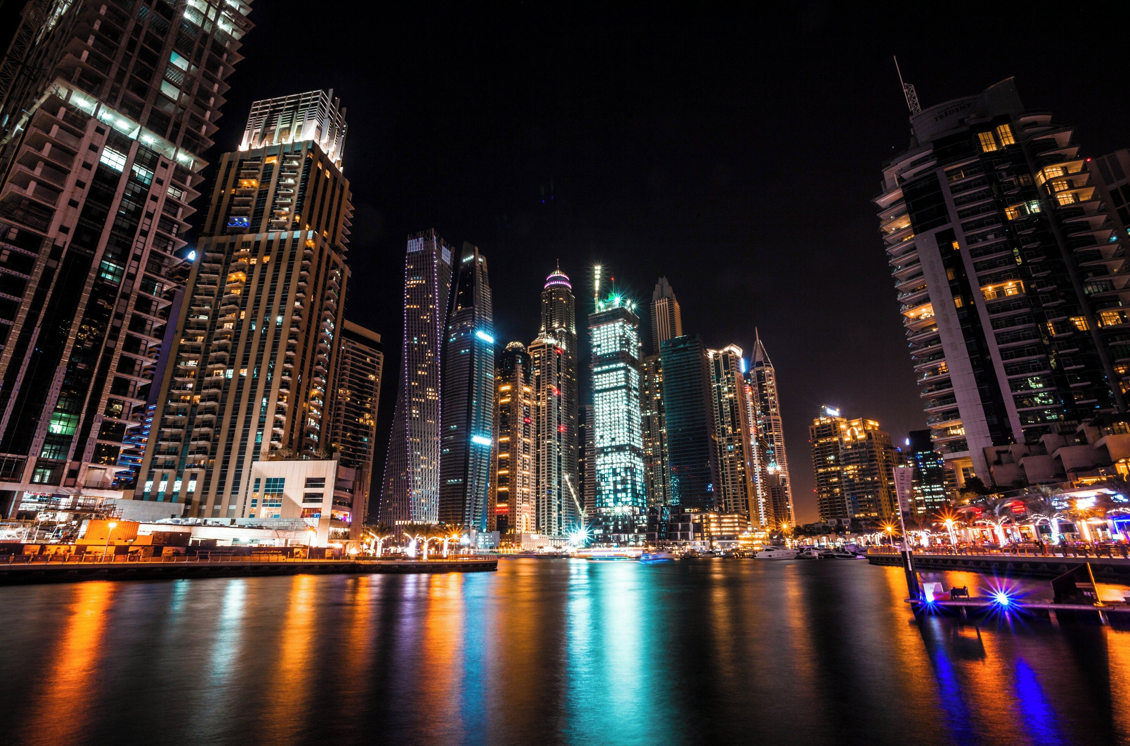 Paisagem urbana noturna com edifícios altos e uma orla marítima.