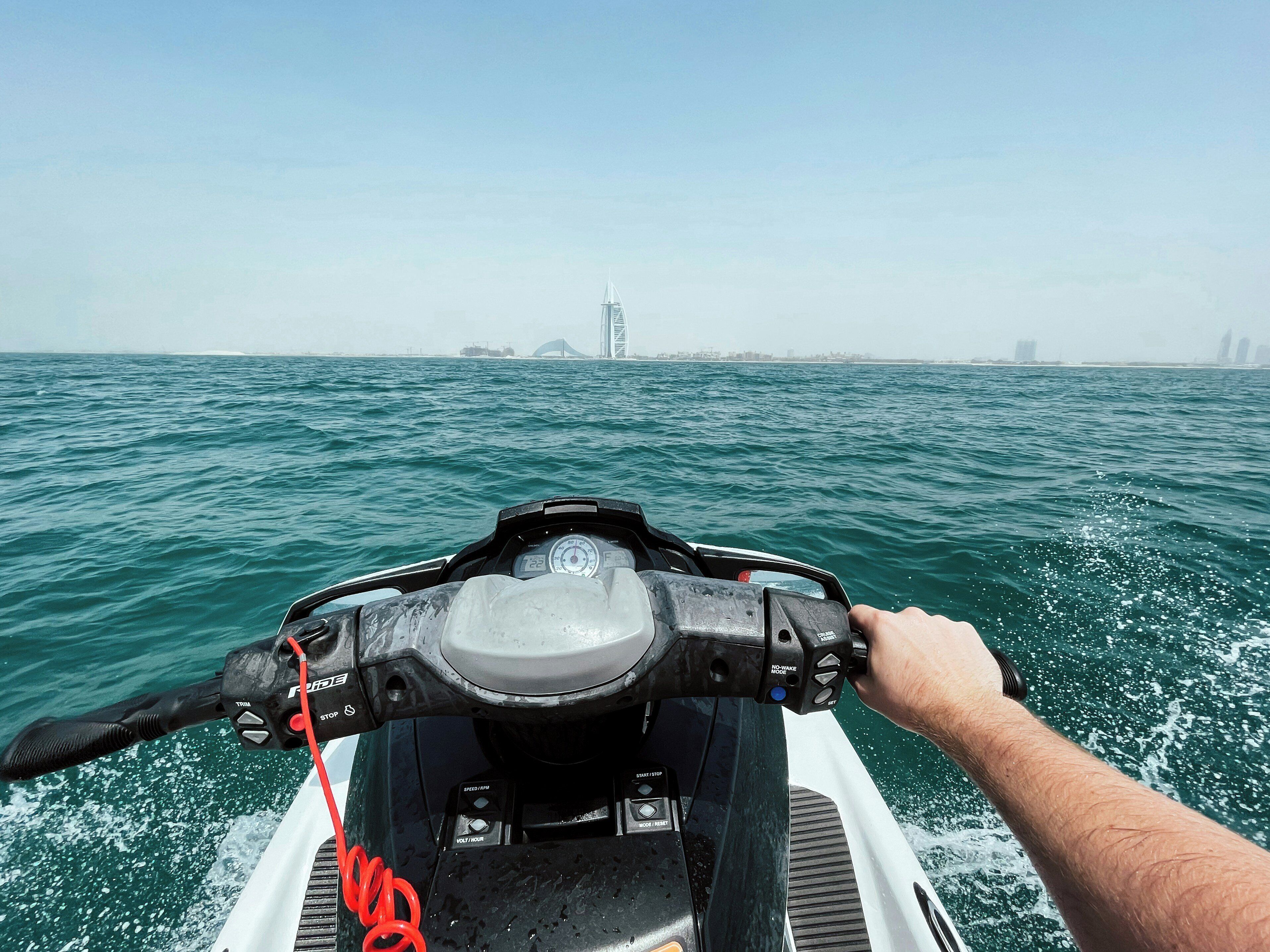 Un jet ski sur l’eau, avec la silhouette d’une ville en arrière-plan.