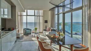 A modern living room with a large glass table, comfortable seating, and a view of the sea. - Th8 Palm Dubai Beach Resort, Vignette Collection by IHG (Dubai)