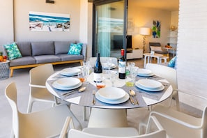 A dining area with a round table set for six, surrounded by white chairs. - Arenal Dream Penthouse I Javea Arenal  Luxury with Roof Terrace & only 150m from the Beach (Javea / Xàbia)