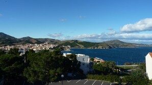 Une ville côtière avec des bâtiments, un parking et une vue sur la mer et les collines.