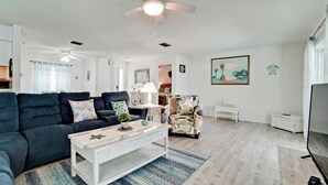 Een woonkamer met een donkerblauwe bank, een witte salontafel en een fauteuil met een patroon.